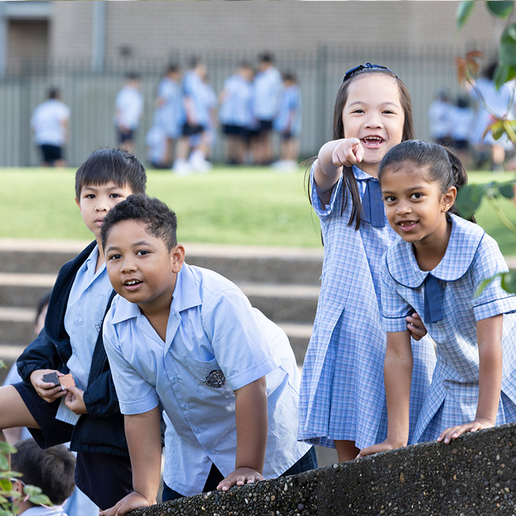 Happy students from St John Vianney's Doonside. 4 students are standing outdoors and pointing at the camera