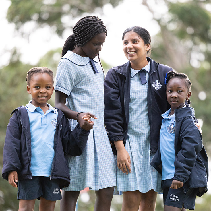 Happy students from St John Vianney's Doonside. 4 girls are standing outdoors holding hands