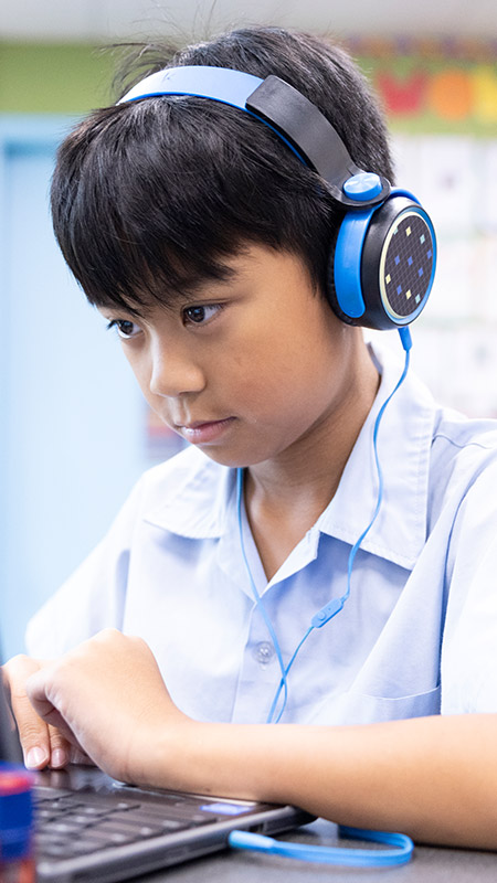 St John Vianney's Doonside student wearing headphones and working off laptop