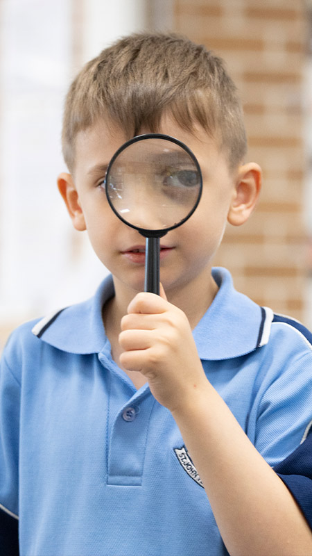 St john Vianney's Doonside student holding a magnifying glass