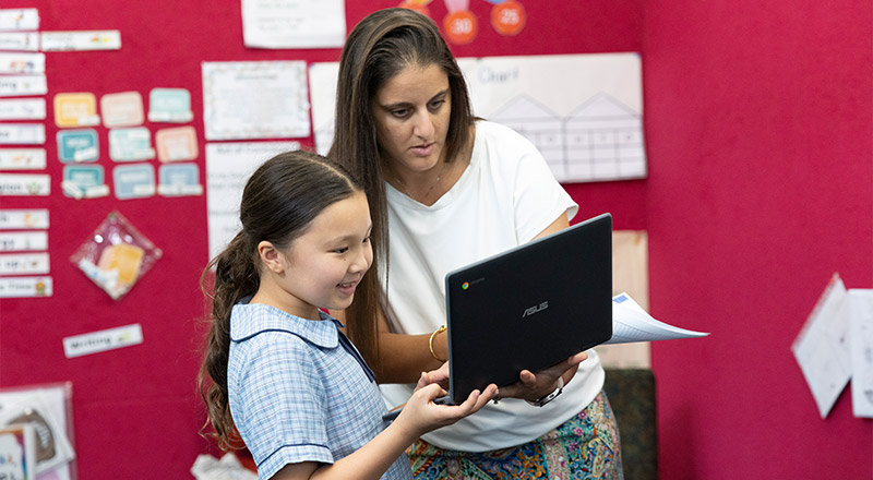 Dedicated Teachers at St John Vianney's Catholic Primary Doonside. Teacher is assisting student in class.