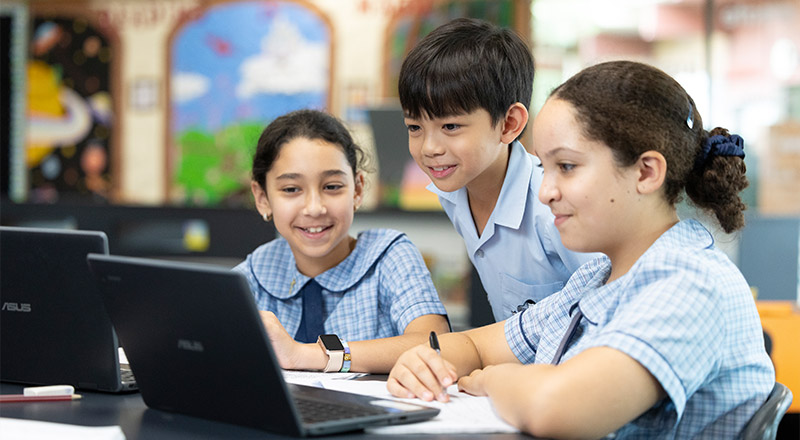 Three St John VIanney's Primary Doonside students in class using technology (Laptop)