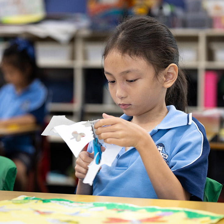 St John Vianney's Doonside student cutting out paper