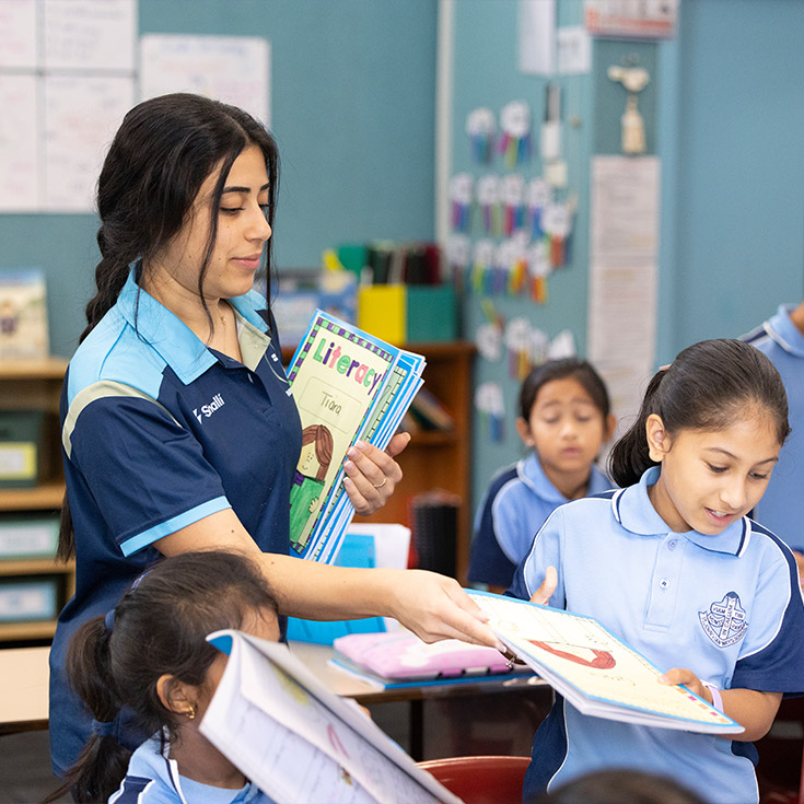 St John Vianney's Doonside teacher handing out classroom resources