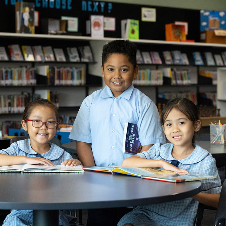 Three happy St John Vianney's Doonside students in the library